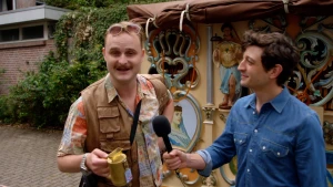 Foto van verslaggever met microfoon bij man voor draaiorgel in Amsterdam.