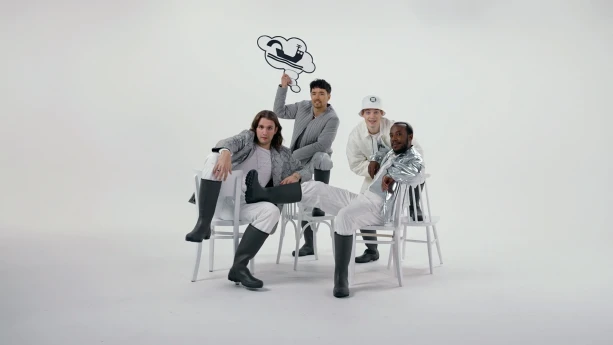 Foto van vier wit en zilver geklede jongens op witte achtergrond die in stoere houdigen poseren op stoelen.