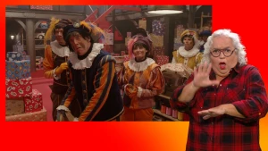 Pieten kijken verschrikt in het pakjesruim. Naast het scherm staat de gebarentolk.