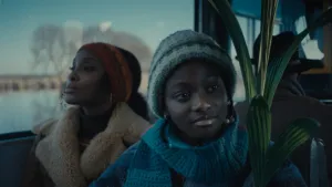 Een foto van twee mensen in een bus die door een winters landschap rijdt, ze hebben een muts op en warme jas aan.