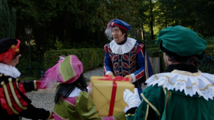 Hoofdpiet spreekt een aantal pieten toe.