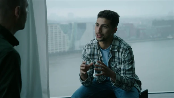 Een foto van presentator Nizar in gesprek met een man. Ze zitten tegenover elkaar. Achter hem uit het raam is een uitzicht over water te zien.