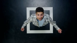 Een foto van presentator Nizar van bovenaf. Hij staat in een hokje dat met witte tape op de vloer gemaakt is.