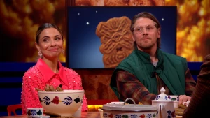 Gasten Marleen en Carlos kijken aandachtig van achter een tafel vol speculaas.