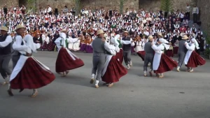Een foto van dansende mensen in Letland, ze dragen Letse klederdracht.