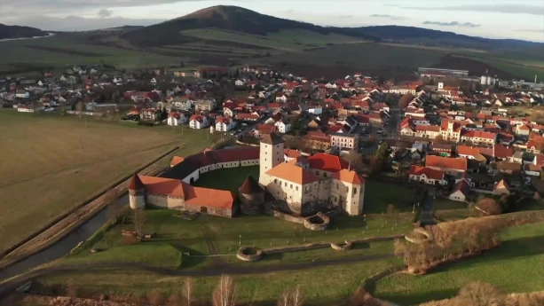 Een foto van een Tsjechisch landschap met heuvels en vooraan een stadje met een burcht.