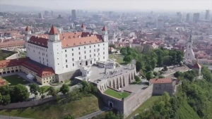 Een foto van de Slowaakse hoofdstad Bratislava met op de voorgrond een groot wit kasteel, daarachter de rest van de stad met hoge gebouwen.