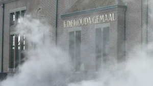 Foto van de gevel van het Woudagemaal waar stoom voor hangt.