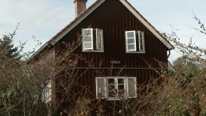 Foto van bruin houten huis met de naam 'Oslo' op de gevel.