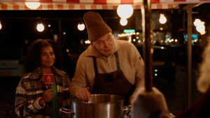 Stephanie staat naast een man die in de soep roert.