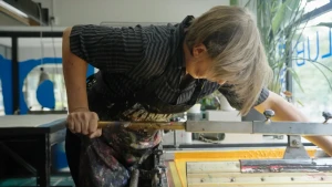 Een man achter een zeefdruk.