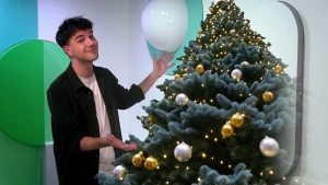 Een foto van presentator Egbert naast een grote kerstboom.