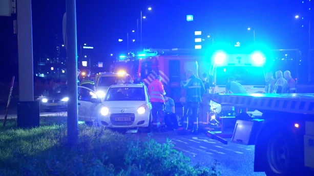 Foto van ongeval op de weg waarbij hulpdiensten aanwezig zijn, je ziet een brandweerauto met blauwe zwaailichten met brandweermensen ernaast.