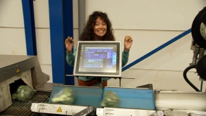 De presentatrice staat achter een weegschaal. 