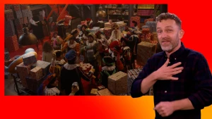 Sinterklaas, de Pieten en Merel vieren feest in het Pakjesruim. Naast het scherm staat de gebarentolk.