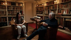 Een meisje en Maarten van Rossum zitten in een bibliotheek.