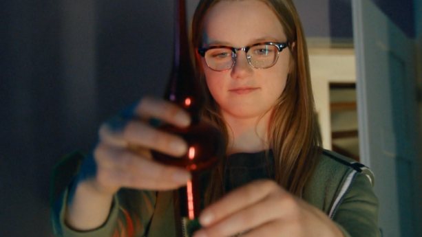 Een foto van een meisje dat de piek op een kerstboompje zet, close up, je ziet alleen haar hoofd en de handen die de piek vasthouden.