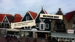 Een still uit de video waarop klassieke Volendamse gebouwen te zien zijn met rode daken. Er zijn twee krantenkoppen met teksten over de brand te zien.