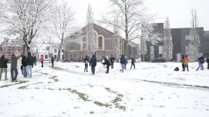 Een afbeelding van een hele groep kinderen in de sneeuw. Zij spelen buiten en bouwen sneeuwpoppen.