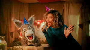 Een foto van de presentator en een ezeltje, ze zitten naast elkaar in een kamer en hebben een feesthoedje op hun hoofd.