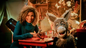 Een foto van de presentatrice en het ezeltje, ze zitten aan een tafel..