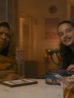 Een foto van een vrouw en een meisje aan een tafel, de vrouw heeft een hoofddoek om, ze kijken richting de camera.