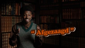 Foto van presentator Anas voor een oude boekenkast, hij kijkt in de camera, en naast zijn handen staat het woord 'afgezaagd'.