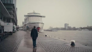 Een foto van een man die over een kade richting een cruiseschip loopt.