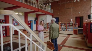 Een foto van de presentator en de schooldirecteur, ze staan in de hal van een oude school uit de jaren '50.