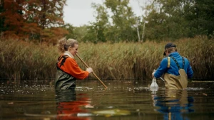 Foto van presentatrice Petra Grijzen samen met een wetenschapper in een sloot om te zoeken naar methaan.