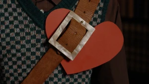 Foto van een rood kartonnen hart dat onder een riem gestoken is.