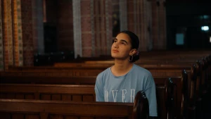 Foto van meisje die op een kerkbank in de kerk zit.