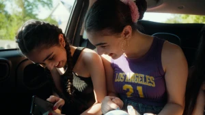 Foto van twee lachende meisjes die naast elkaar in een auto zitten.