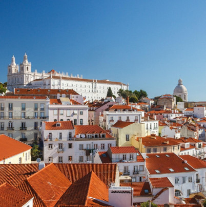 Foto van Portugese stad met witte gebouwen en oranje daken met een blauwe lucht. 