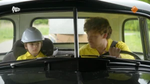 Foto van kind met bouwhelm die samen met Soy Kroon in een auto zit.