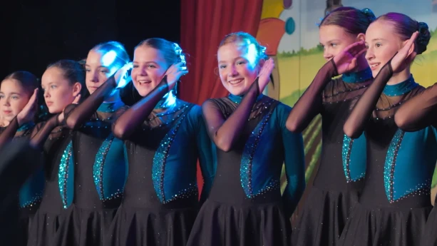 Foto van meisjes die in danskleding een dans opvoeren.