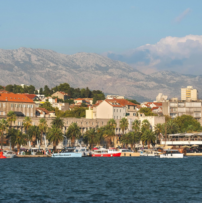 Stad aan de zee met bergen in de achtergrond.