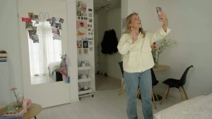 Foto van influencer Emma Keuven die met haar telefoon in haar hand zichzelf filmt.