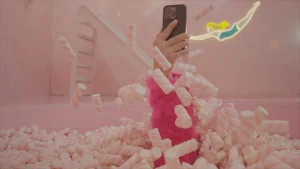 Foto van een bad vol snoepspekjes met een arm die eruit steekt en een telefoon vasthoudt.