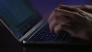 Foto van laptop met iemand zijn handen.