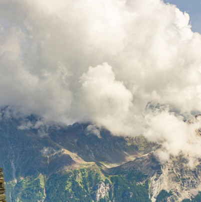 Zwitserse vlag met op de achtergrond bergen en wolken.