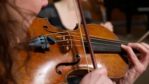 Foto van viool die bespeeld wordt door vrouw met donker haar.